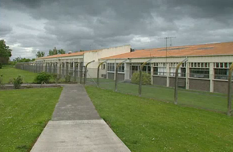 Photo of the maximum security villa.  The building is surrounded by a high wire fence.